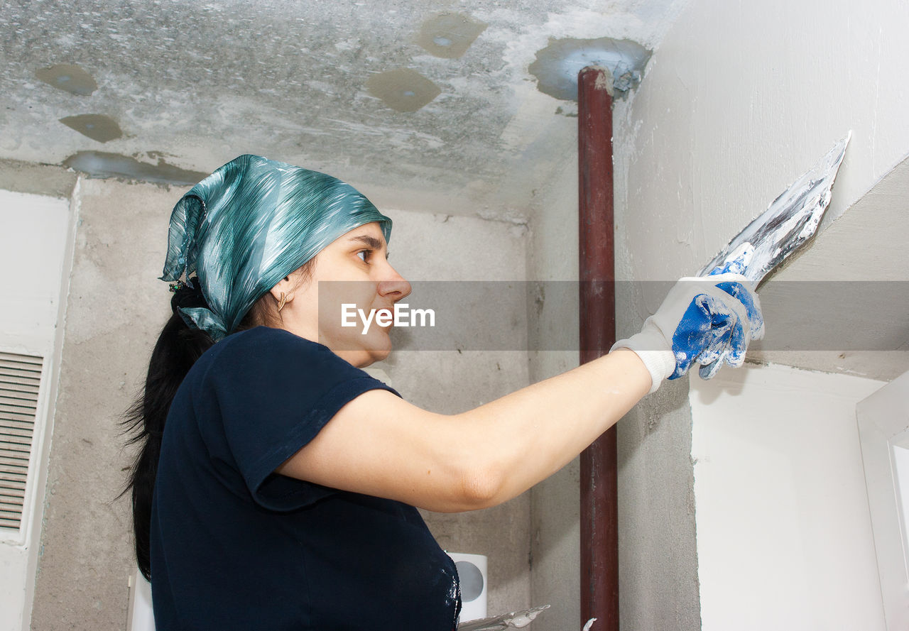 Woman plastering wall at home