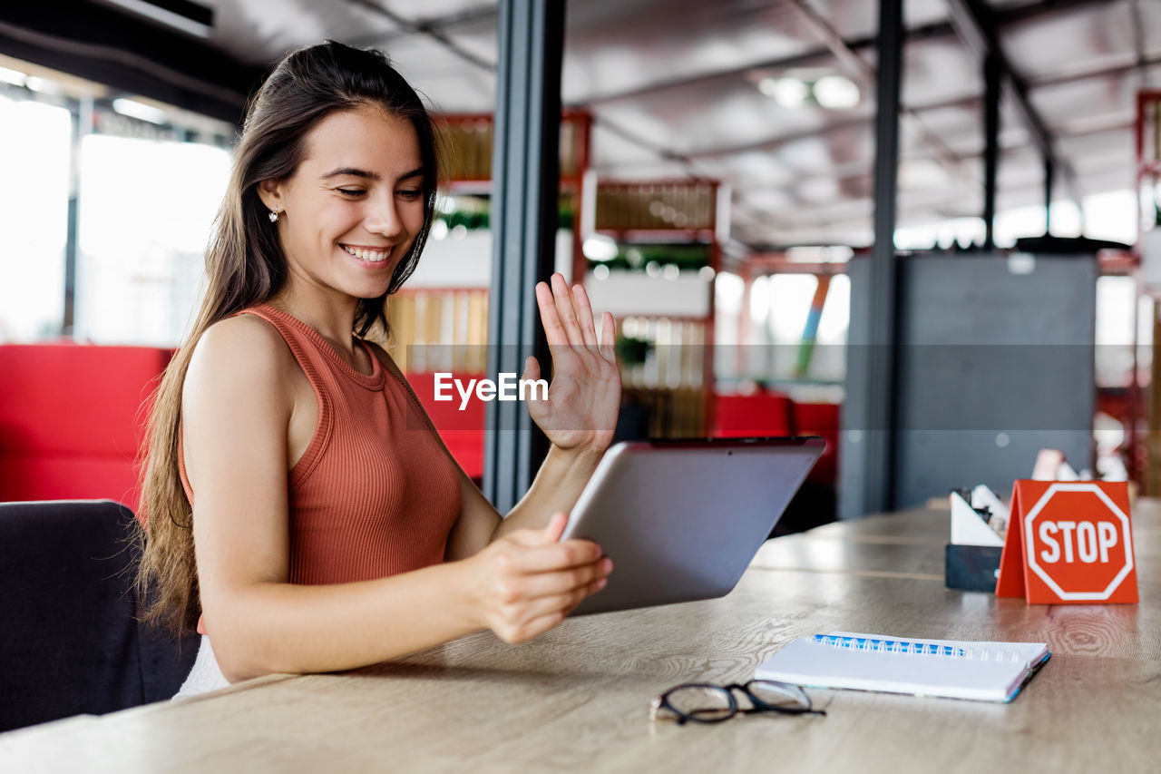 A young girl waves a webcam in a tablet computer, holding a virtual online meeting with her friend