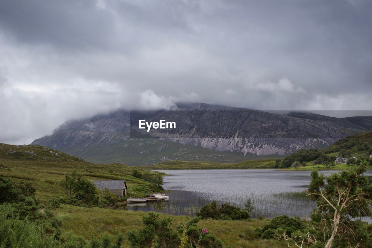 Scenic view of mountains and lake against cloudy sky