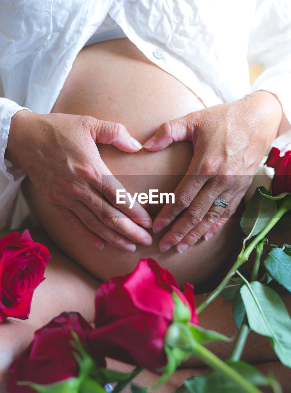 Midsection of pregnant woman with flowers