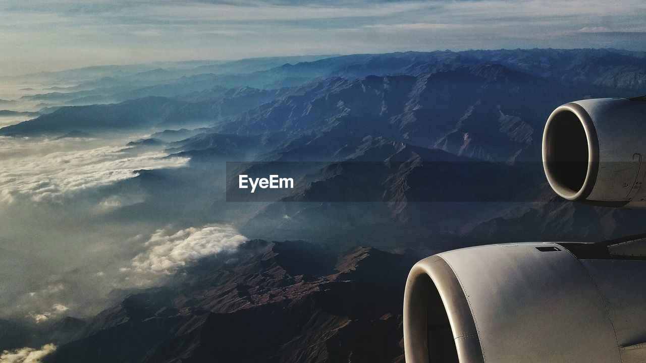 Cropped image of airplane flying over mountains