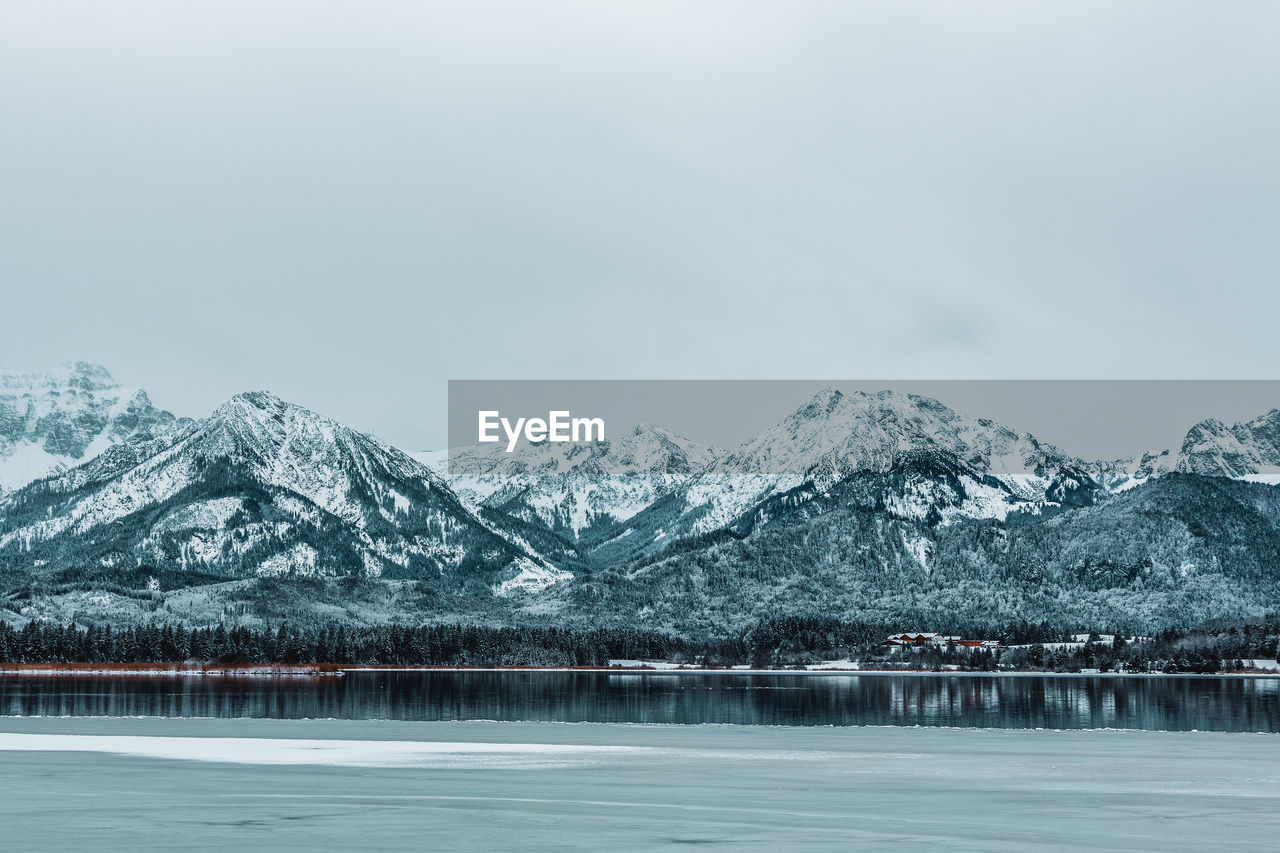 Scenic view of lake by snowcapped mountains against sky