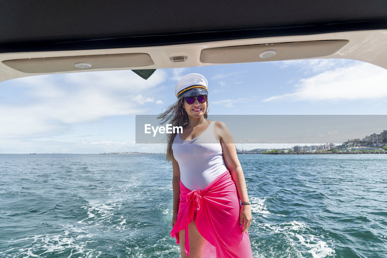 Portrait of young woman standing against sea