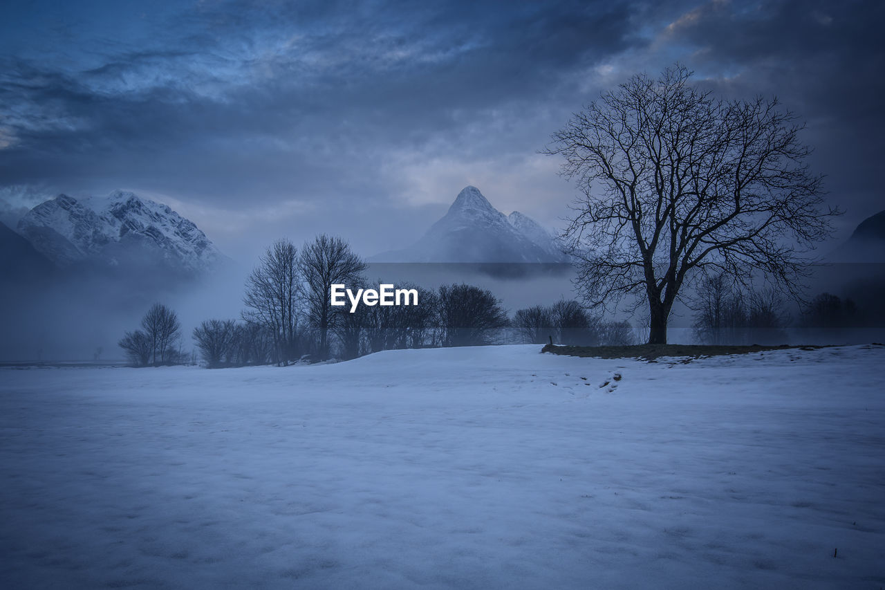 Scenic view of snow covered mountains against cloudy sky