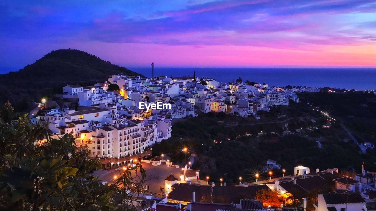 High angle view of townscape by sea against sky at dusk