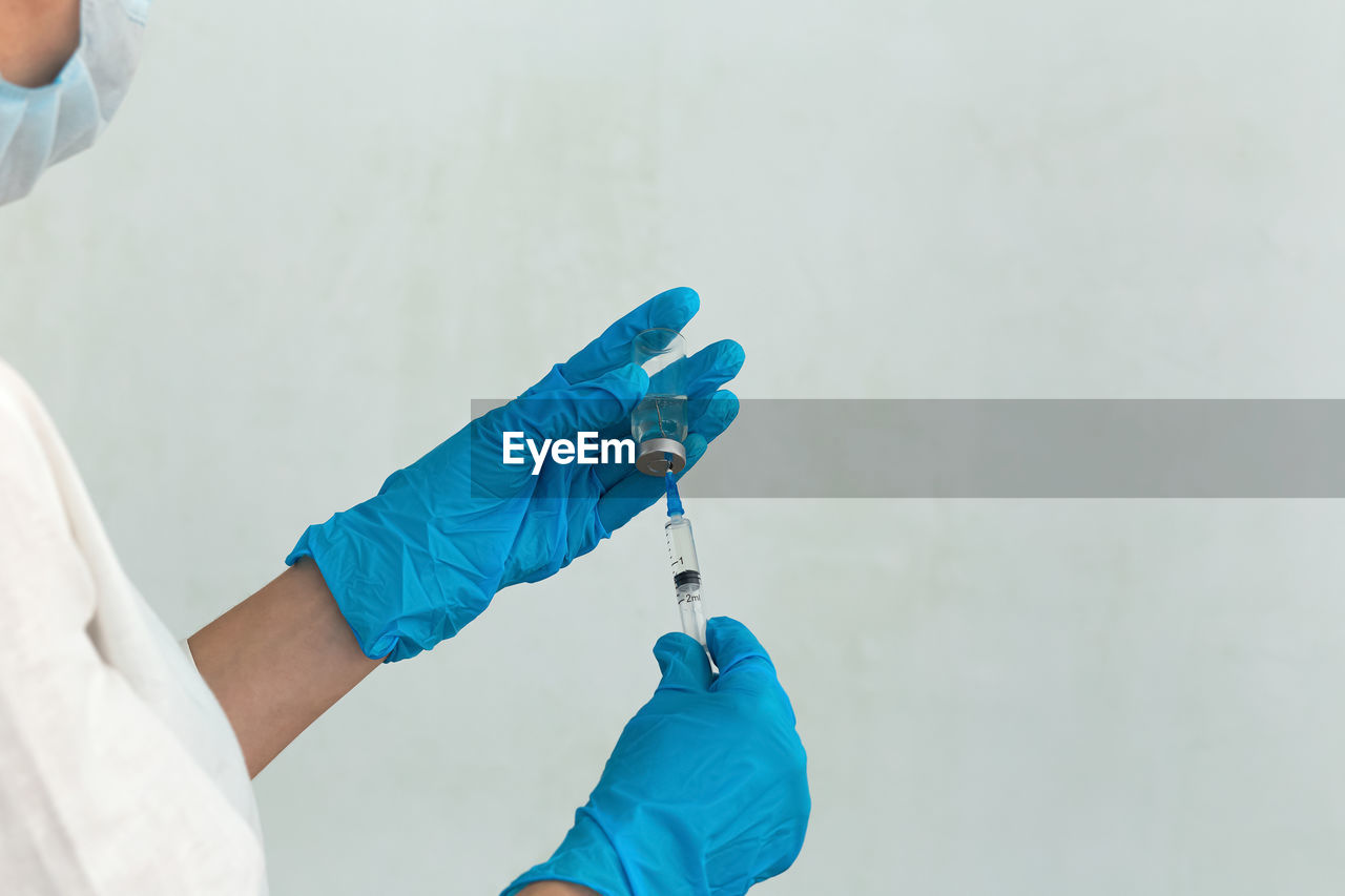 Cropped hands of doctor holding syringe with vial at hospital