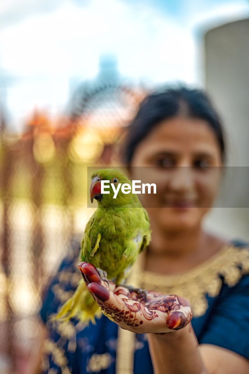 Woman with henna tattoo holding parrot