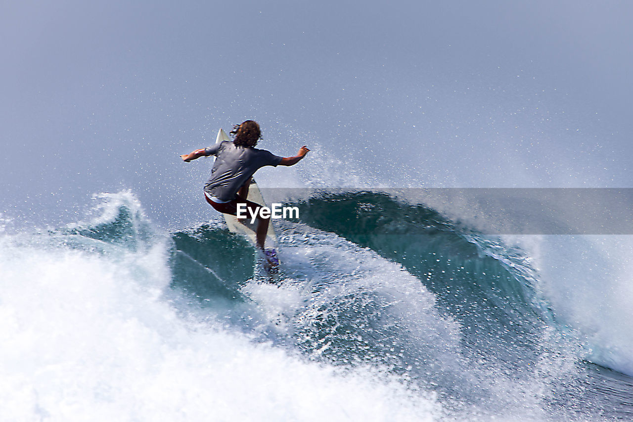 Rear view of man surfing on sea waves