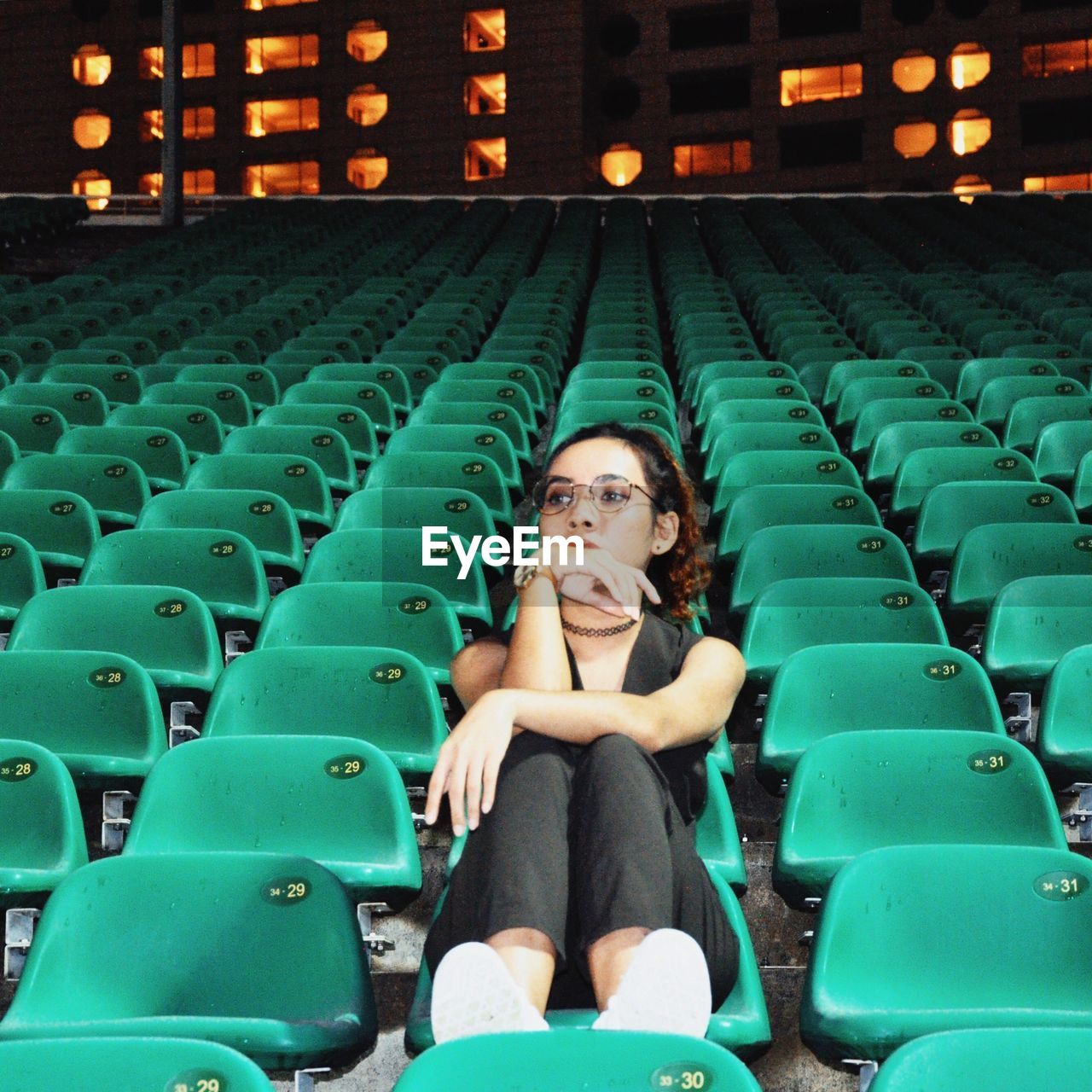 Full length of young woman sitting at stadium