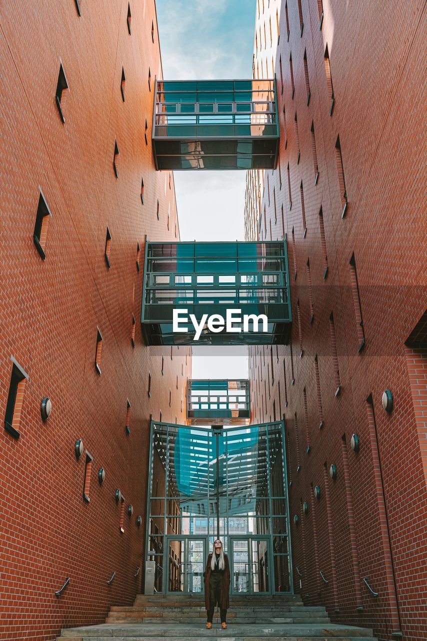 PEOPLE WALKING BY MODERN BUILDING IN CITY