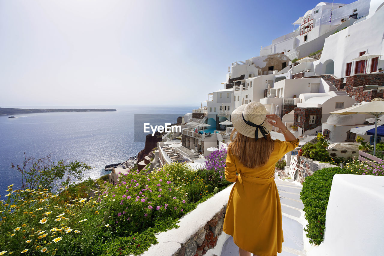 Young beautiful girl walking in oia village on santorini island, greece.