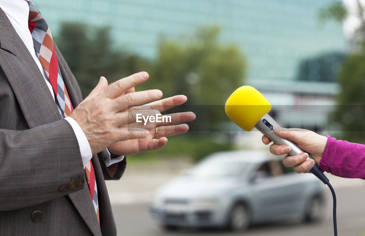 Cropped hand of reporter interviewing businessmen