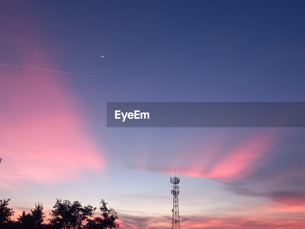 LOW ANGLE VIEW OF COMMUNICATIONS TOWER AGAINST SKY DURING SUNSET