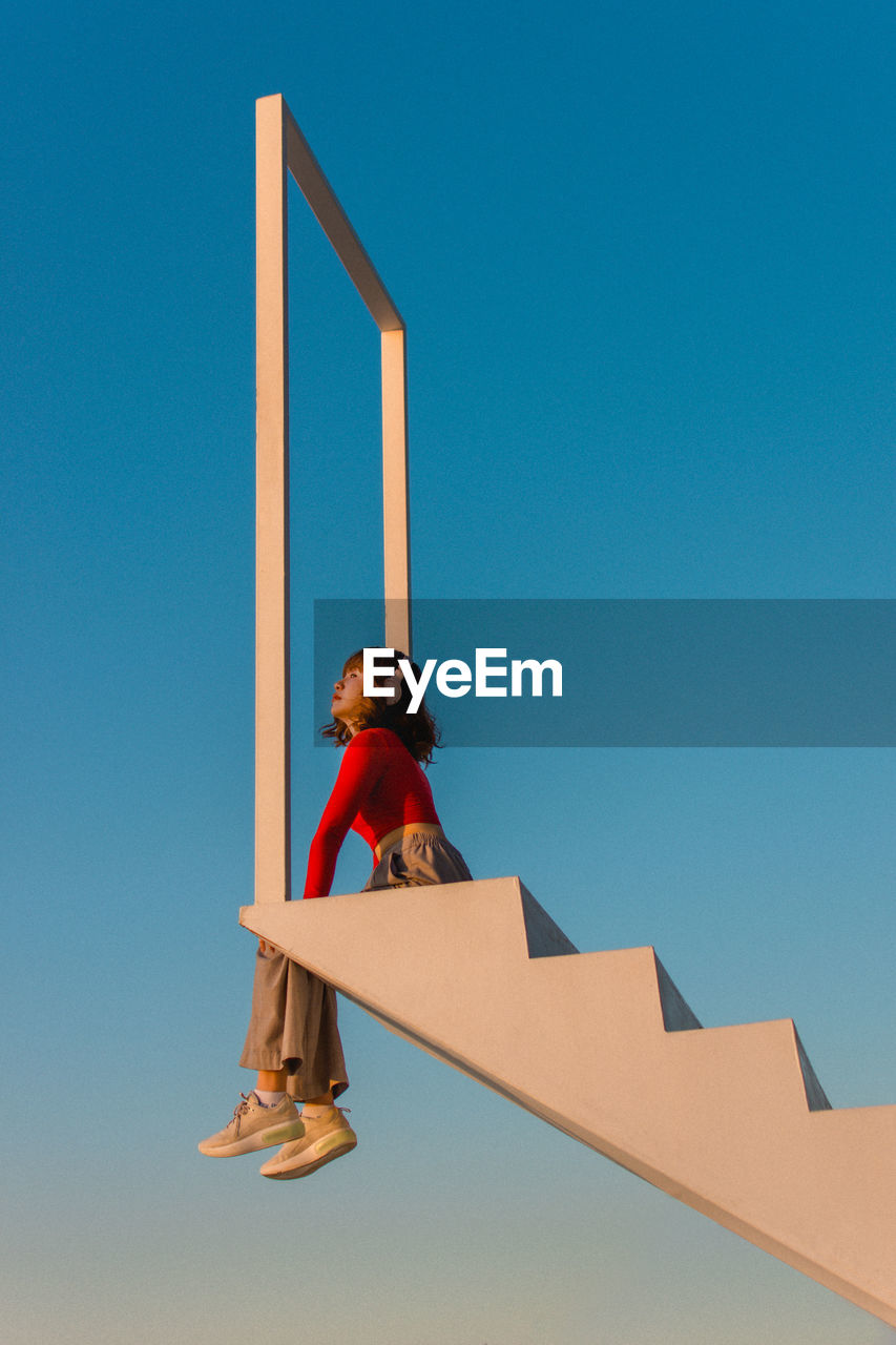 LOW ANGLE VIEW OF WOMAN AGAINST SKY