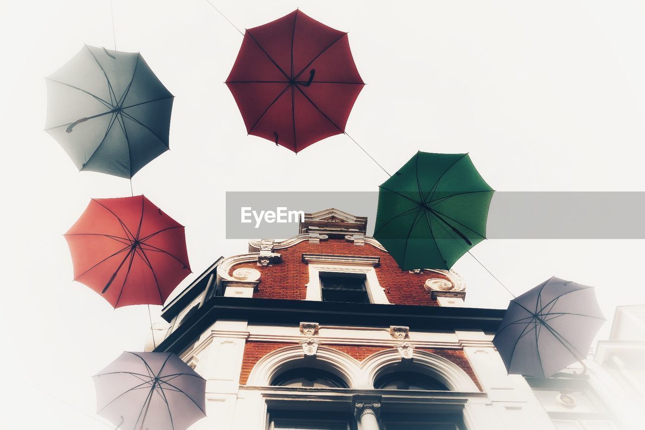 LOW ANGLE VIEW OF UMBRELLA AGAINST BUILDING