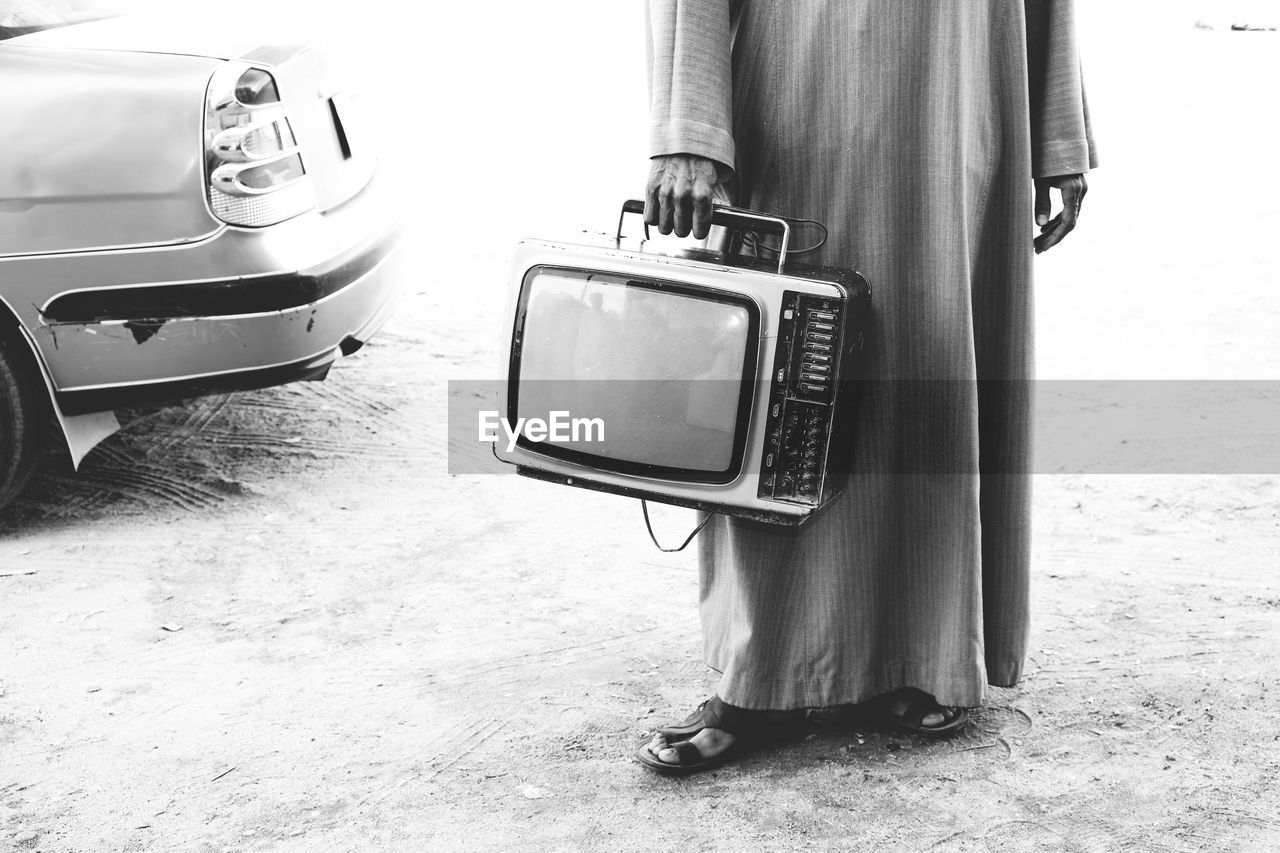 Low section of man holding an old tv
