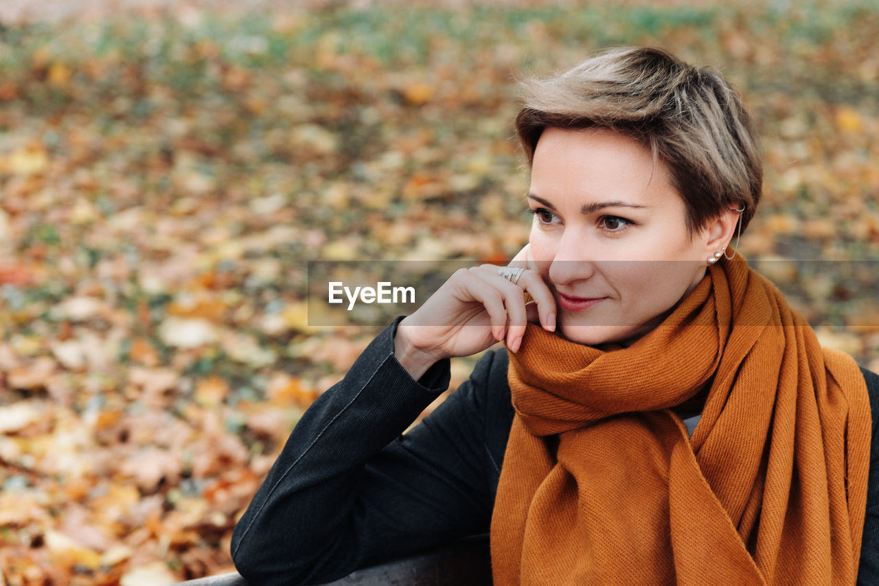 A brooding short-haired woman in autumn in a terracotta scarf