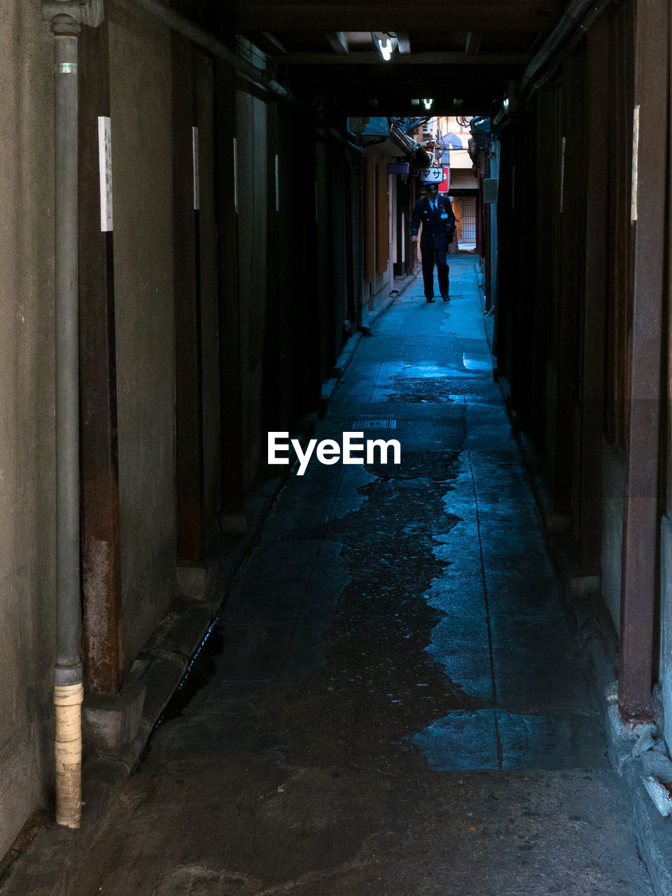 MAN WALKING IN CORRIDOR OF BUILDING