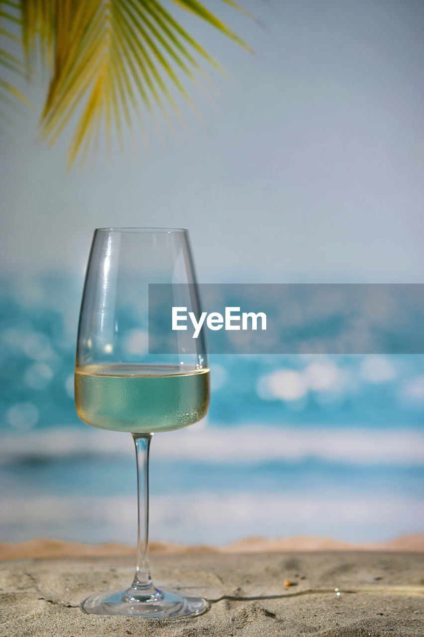 Closeup summer white wine glass on sand beach