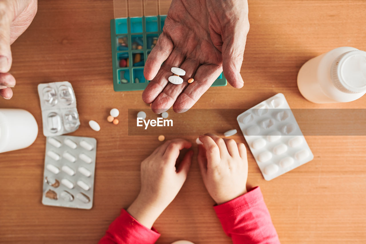 Grandchild helping grandfather to organize medication into pill dispenser. healthcare concept