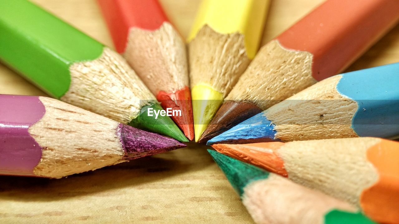 Close-up of colored pencils arranged on wooden table