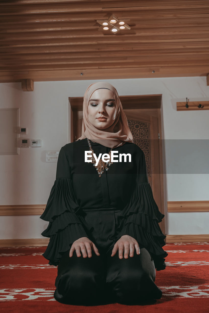 Woman in traditional clothing praying at mosque