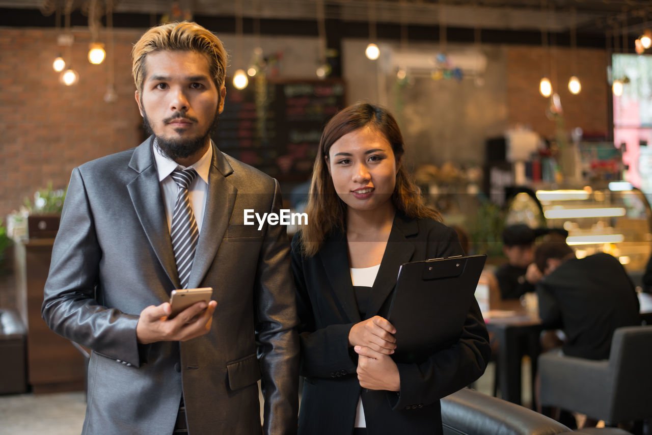 Businesswoman and colleague using mobile phone at cafe