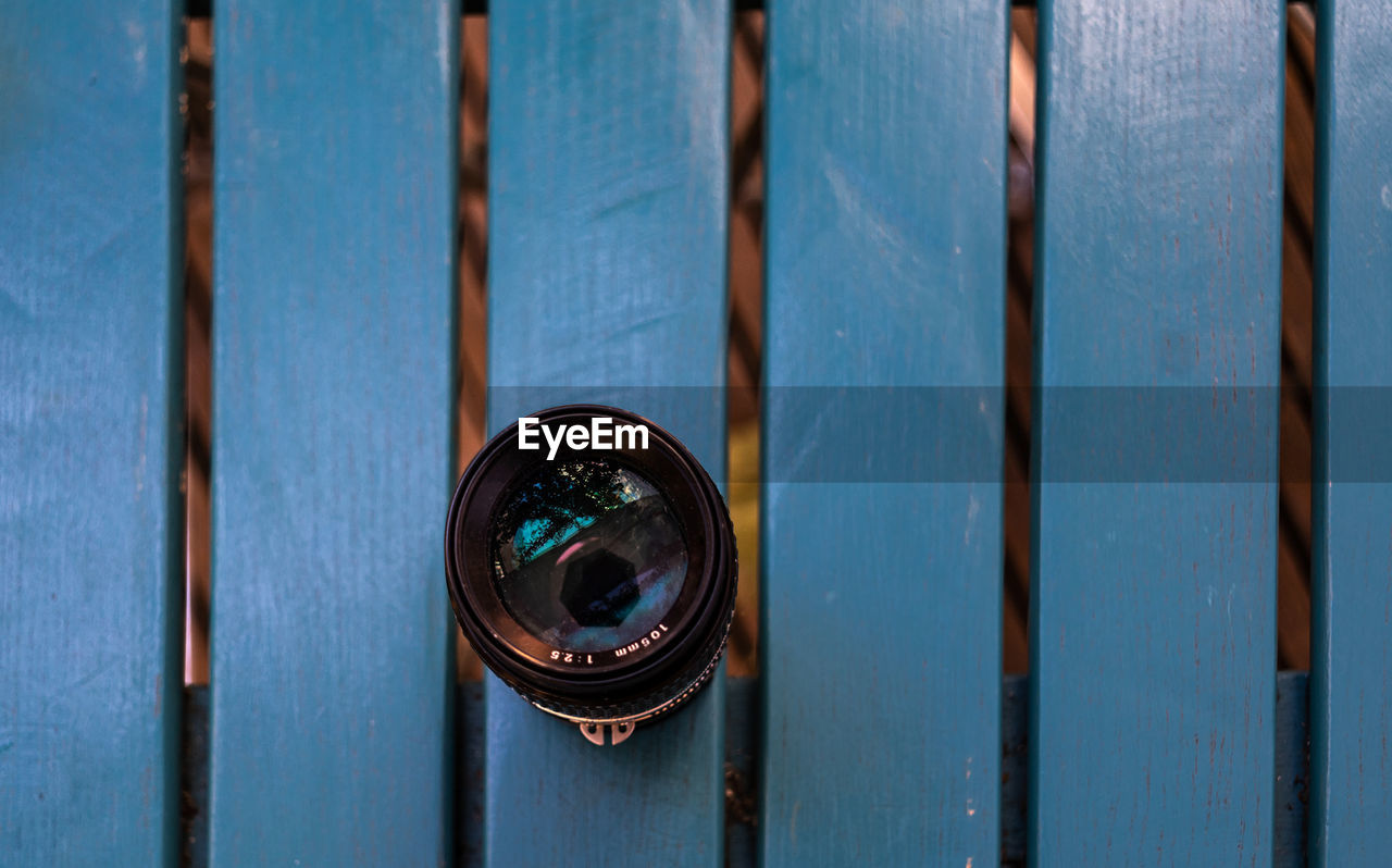 Directly above shot of camera lens on wooden bench