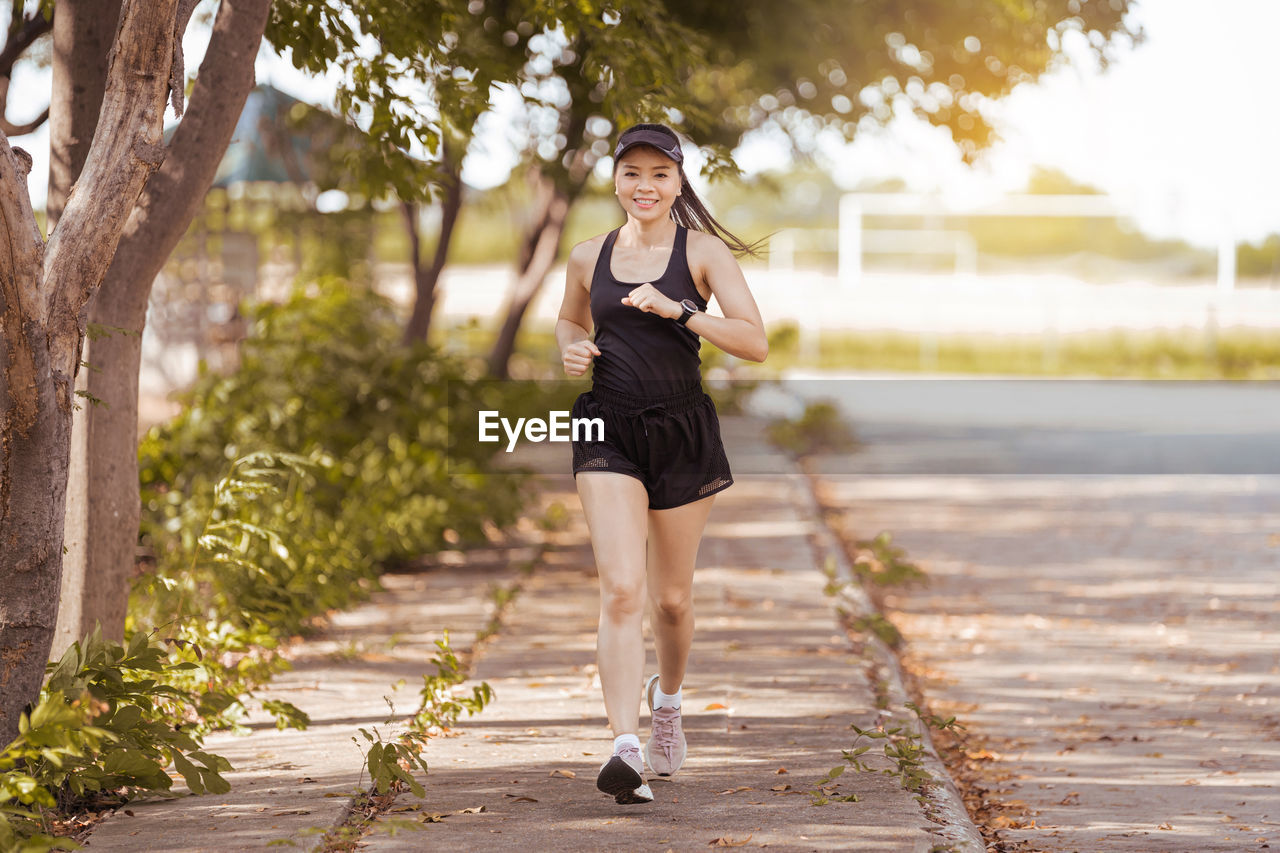 Full length portrait of woman standing on footpath