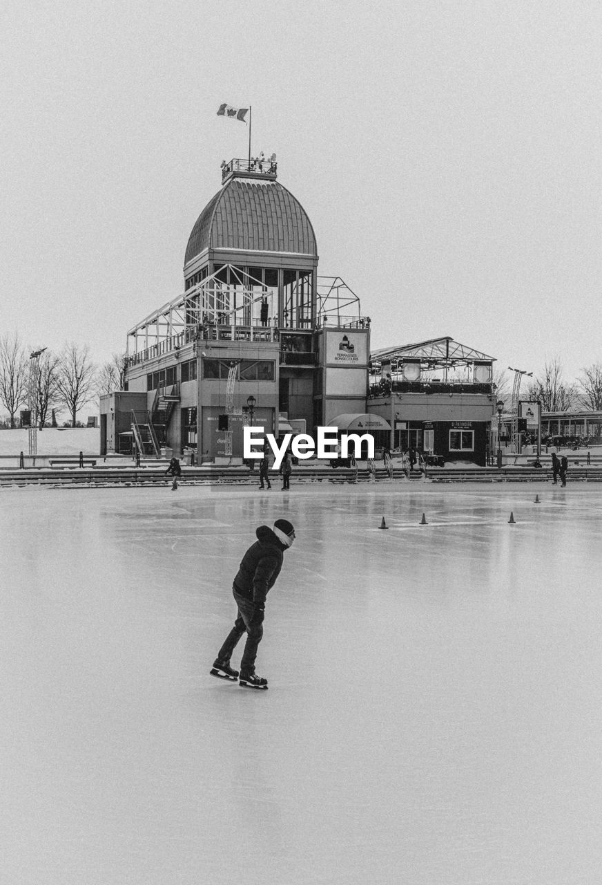 architecture, ice skating, built structure, building exterior, snow, black and white, men, nature, one person, travel destinations, water, full length, day, winter, dome, sky, city, monochrome photography, monochrome, ice rink, person, travel, winter sports, lifestyles, footwear, leisure activity, cold temperature, tourism, adult, outdoors, building