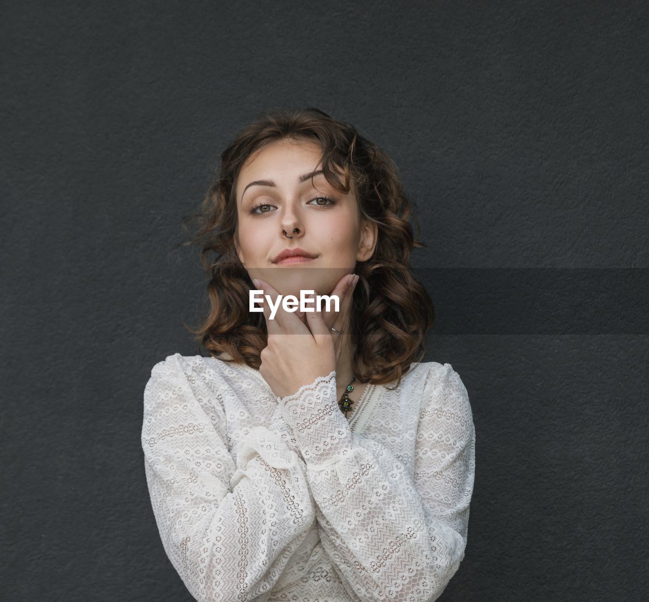 Portrait of young woman standing against black background