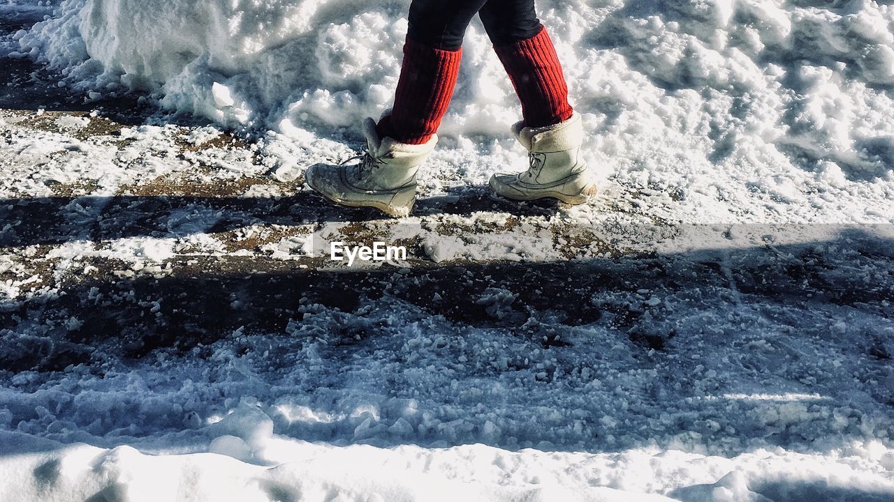 Low section of person walking on snowy road