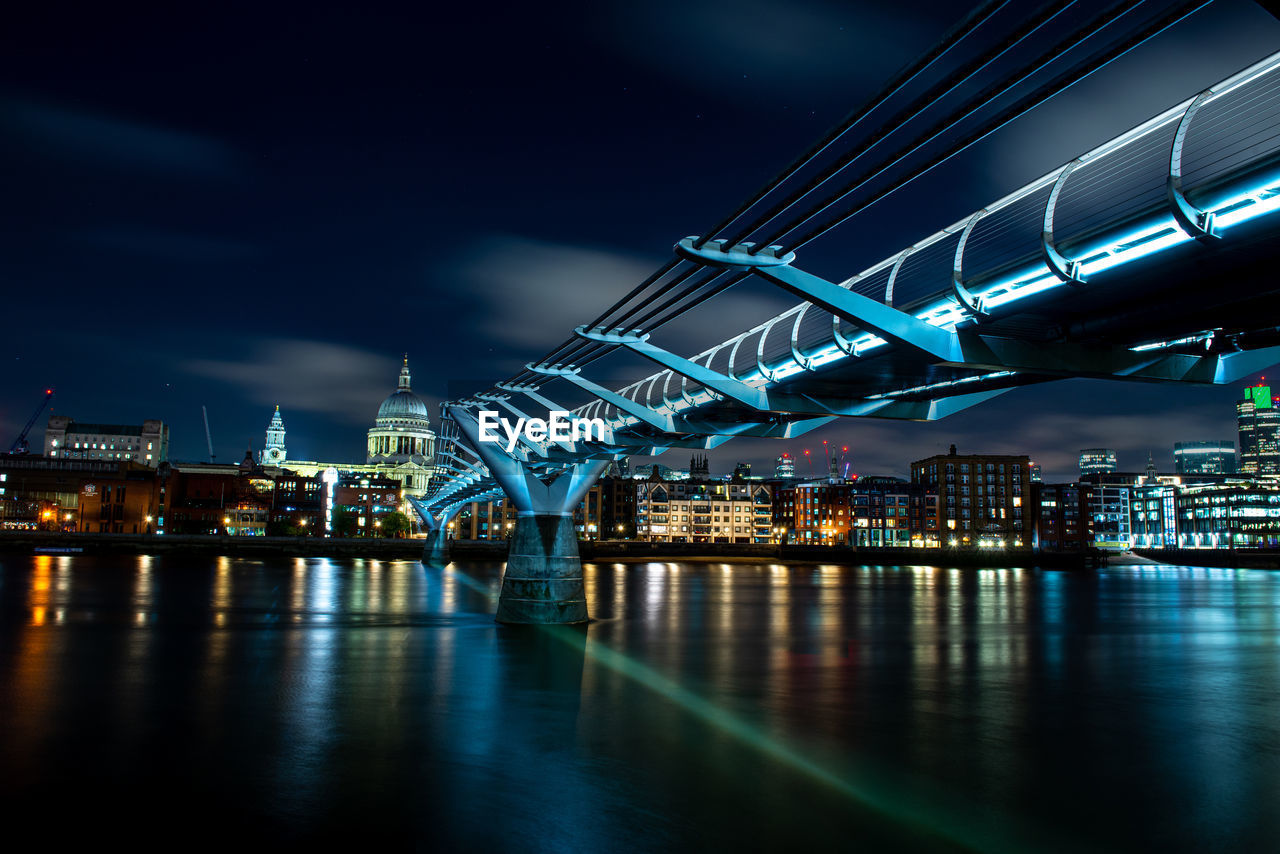 Illuminated bridge over river against sky at night