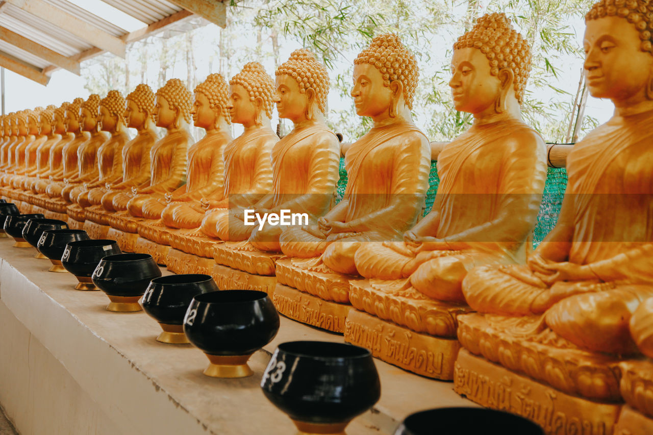 Line of golden statues of buddah in the phra phutta ming mongkol akenakiri in thailand in phuket.