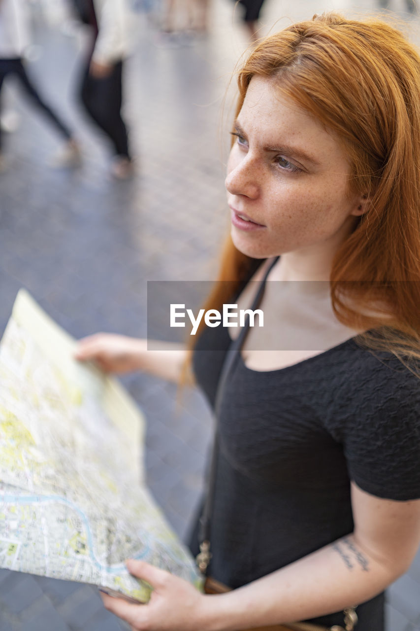 Portrait of a woman standing in the city holding a city map