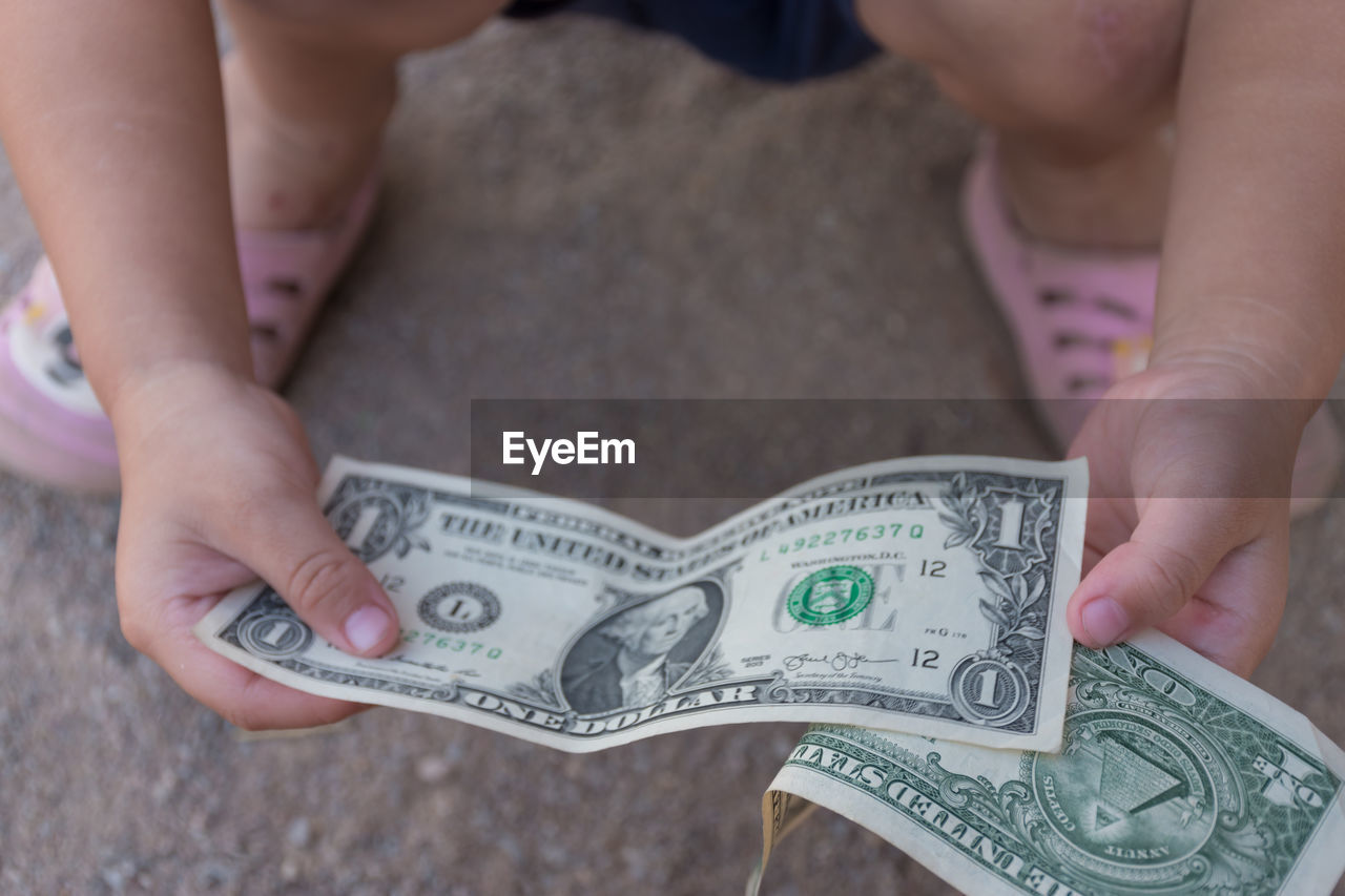 Low section of baby holding paper currencies