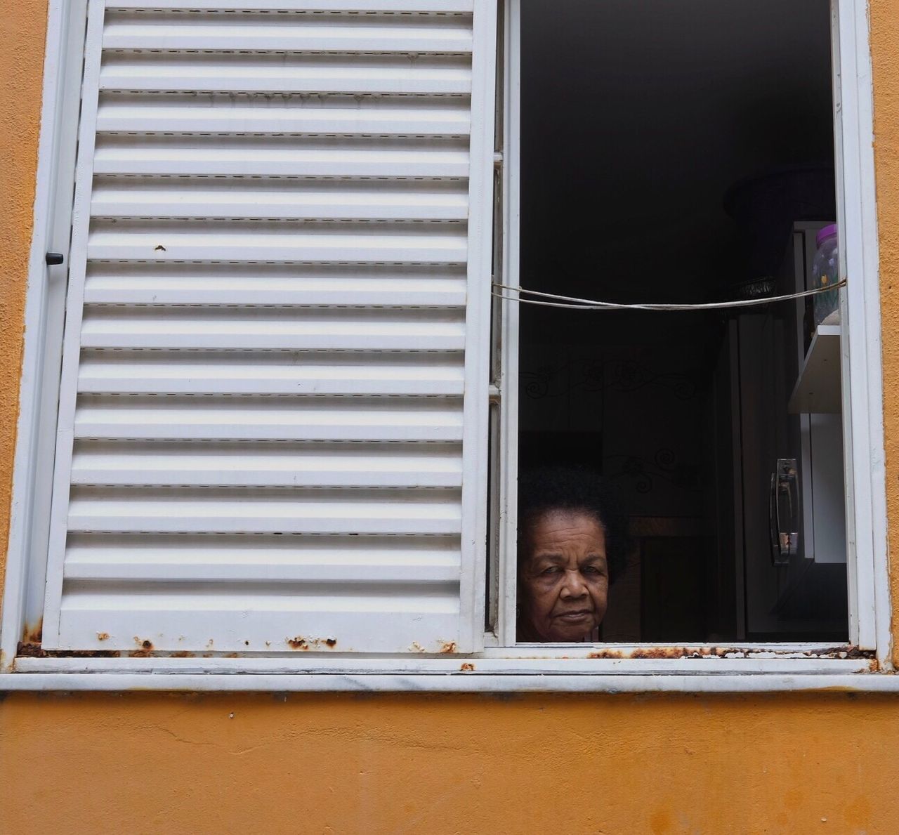 MAN SEEN THROUGH WINDOW SHUTTER