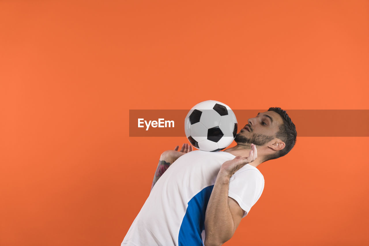 rear view of man with ball against yellow background
