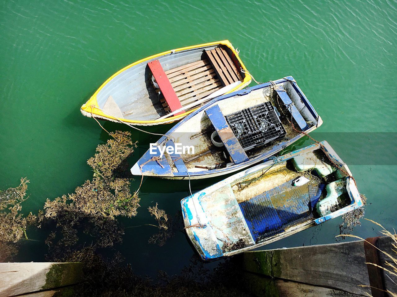 HIGH ANGLE VIEW OF ABANDONED BOAT MOORED BY LAKE