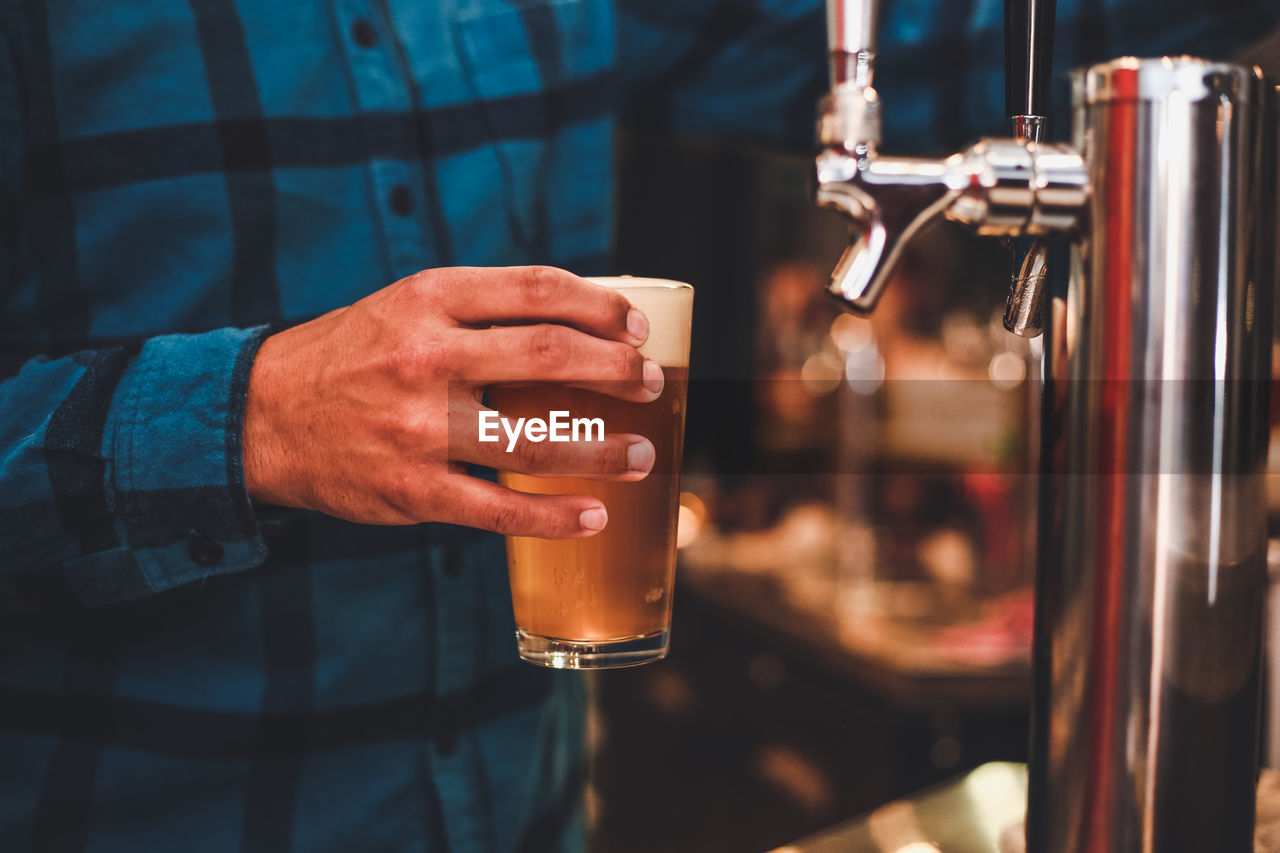 Midsection of man holding of beer glass