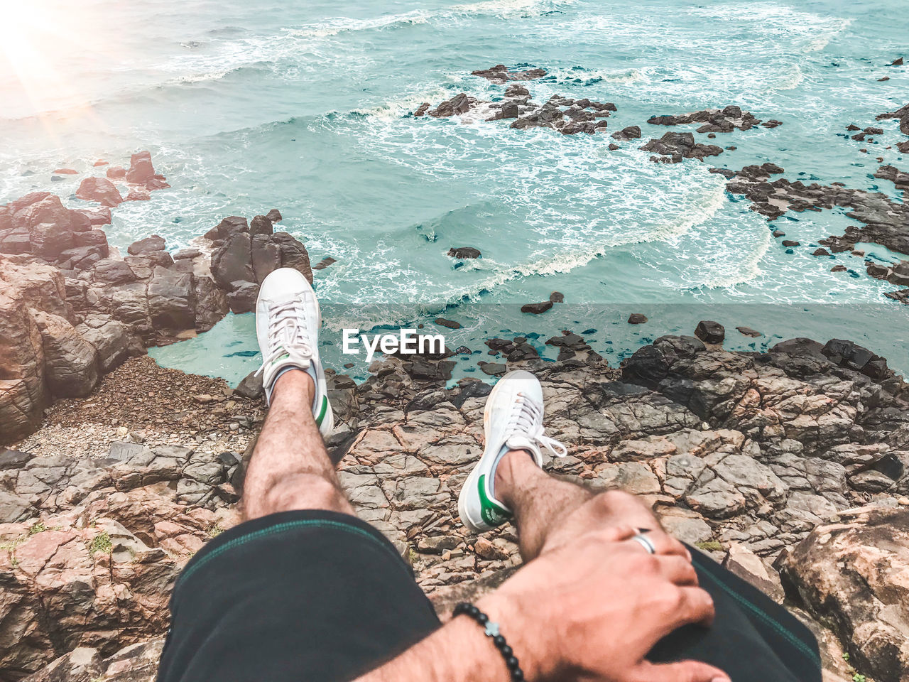 LOW SECTION OF PERSON ON ROCK AT SEA