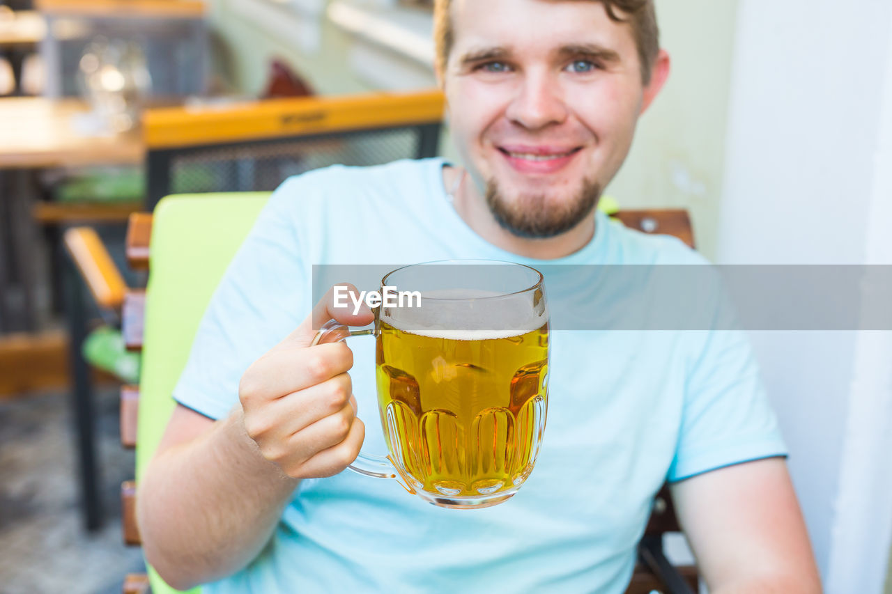 close-up of young woman holding beer in cafe