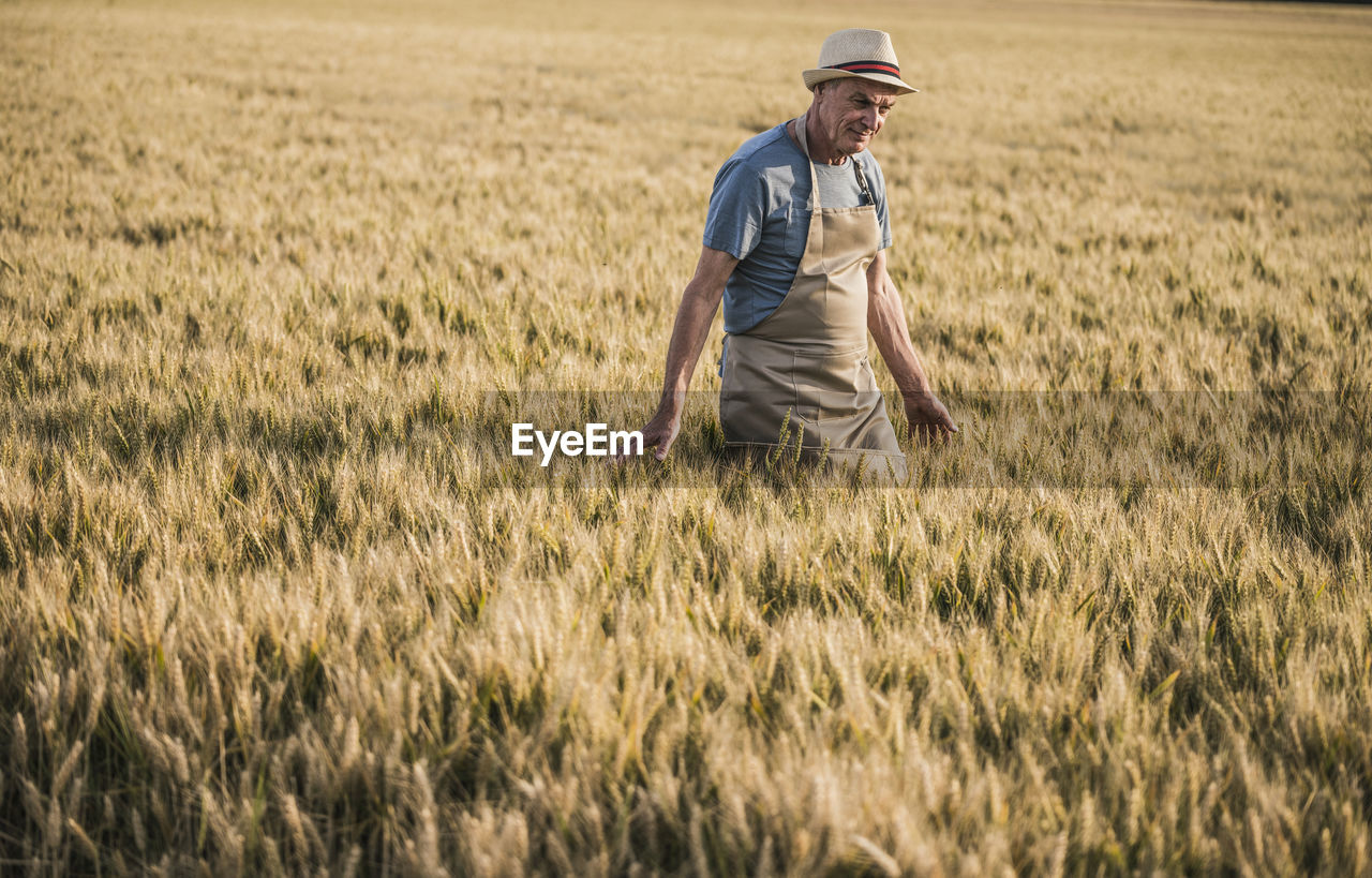 Senior farmer wearing hat walking in field
