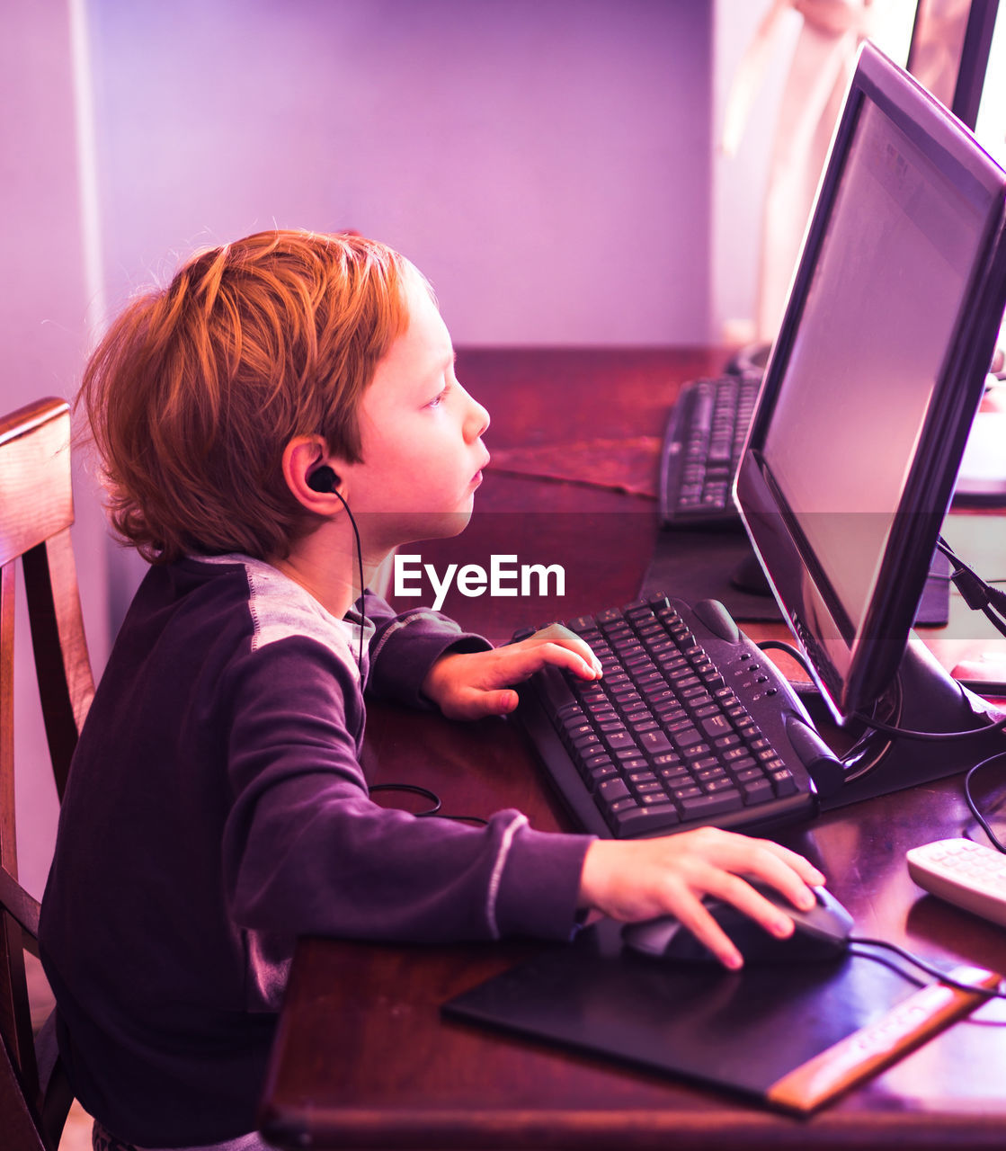 Side view of boy using computer at table