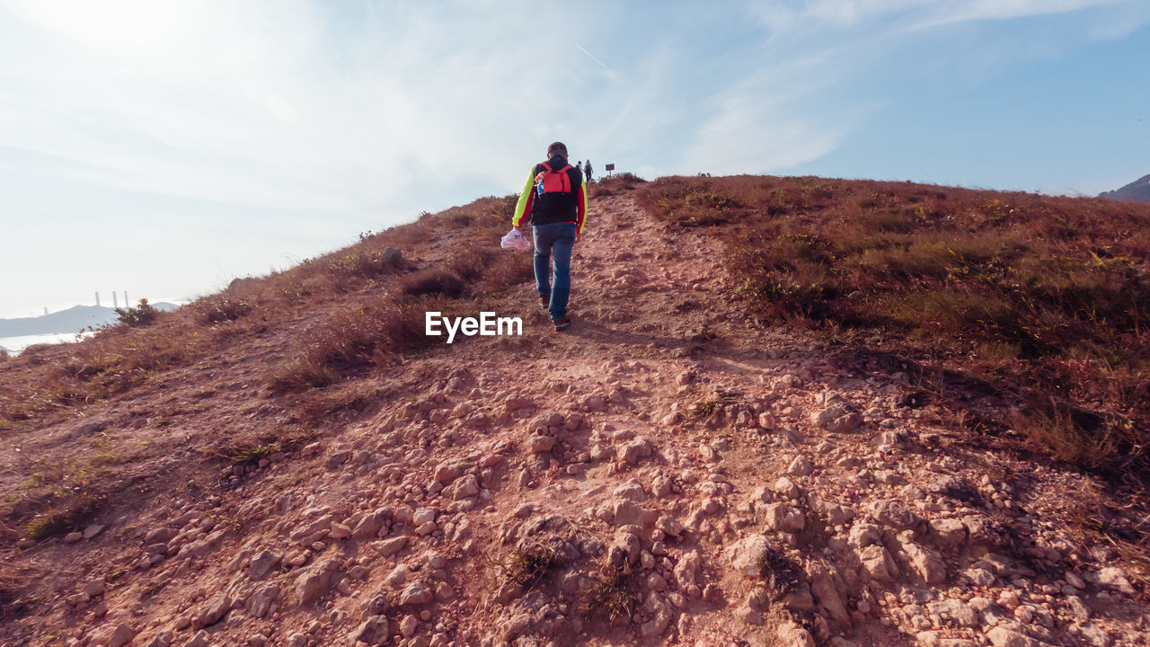 REAR VIEW OF MAN STANDING ON MOUNTAIN