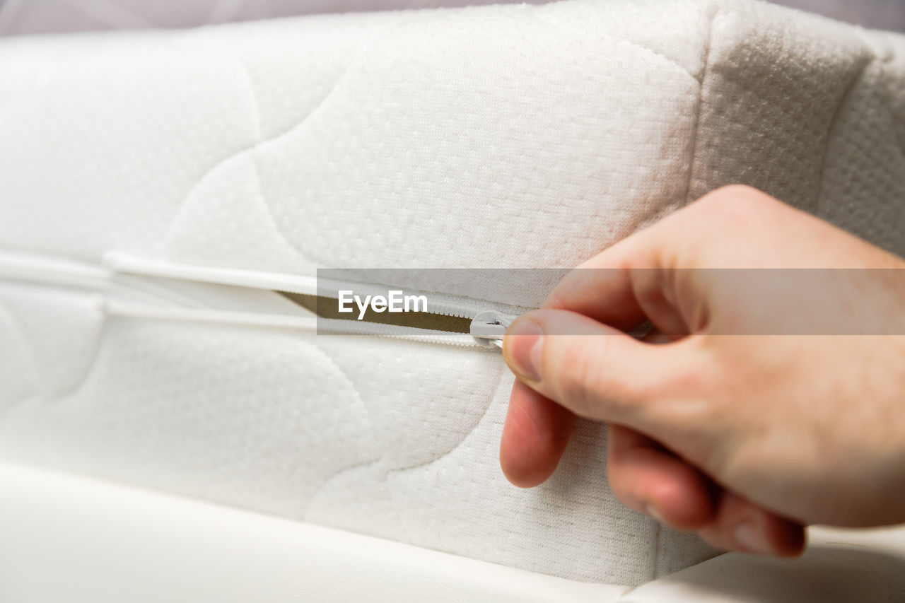 CLOSE-UP OF PERSON HOLDING PAPER WITH HAND ON WHITE BACKGROUND