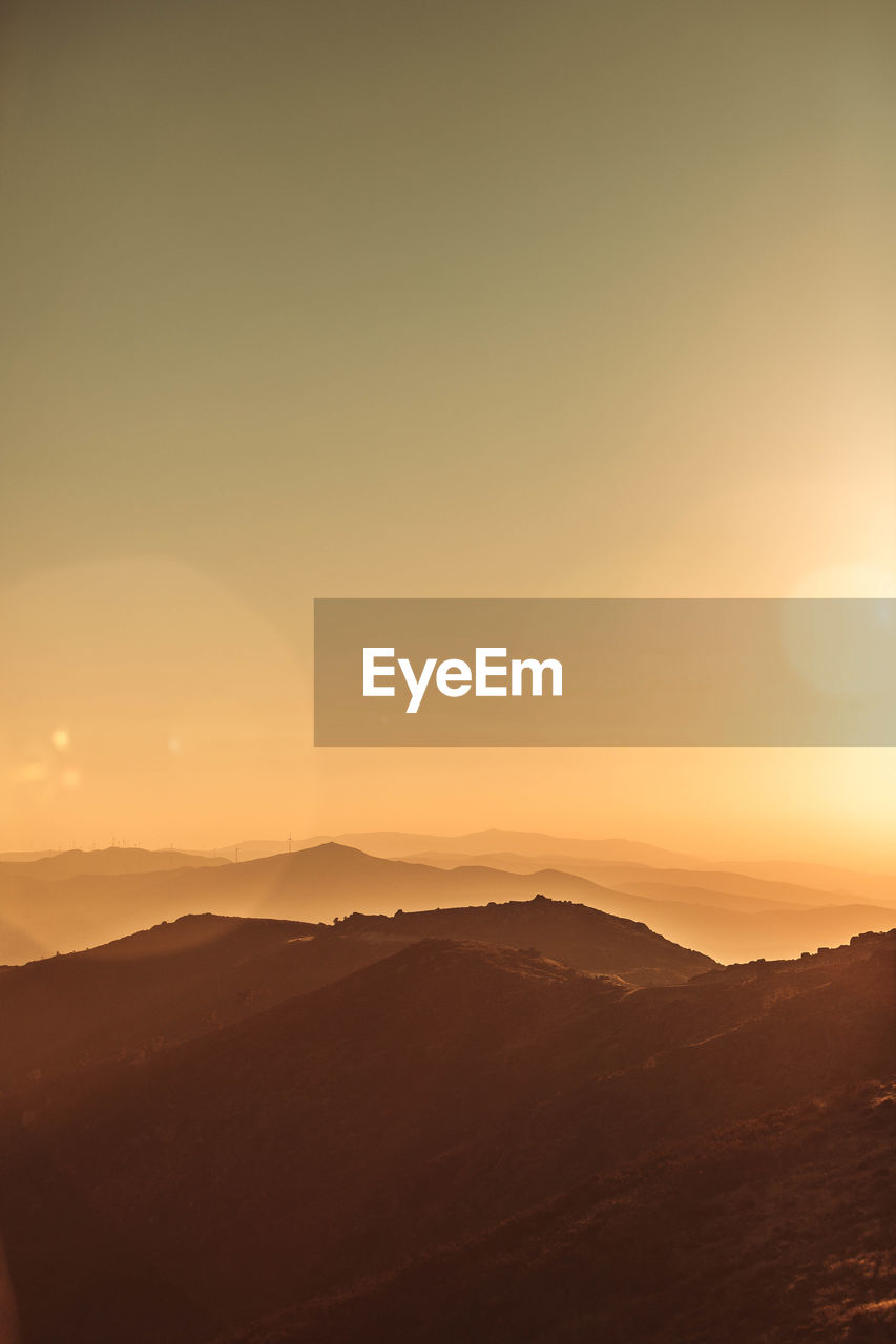 scenic view of silhouette mountains against clear sky during sunset