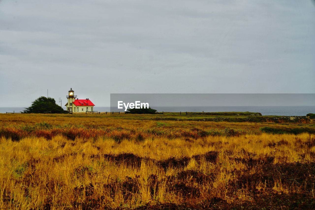 Scenic view of light house and field against sky