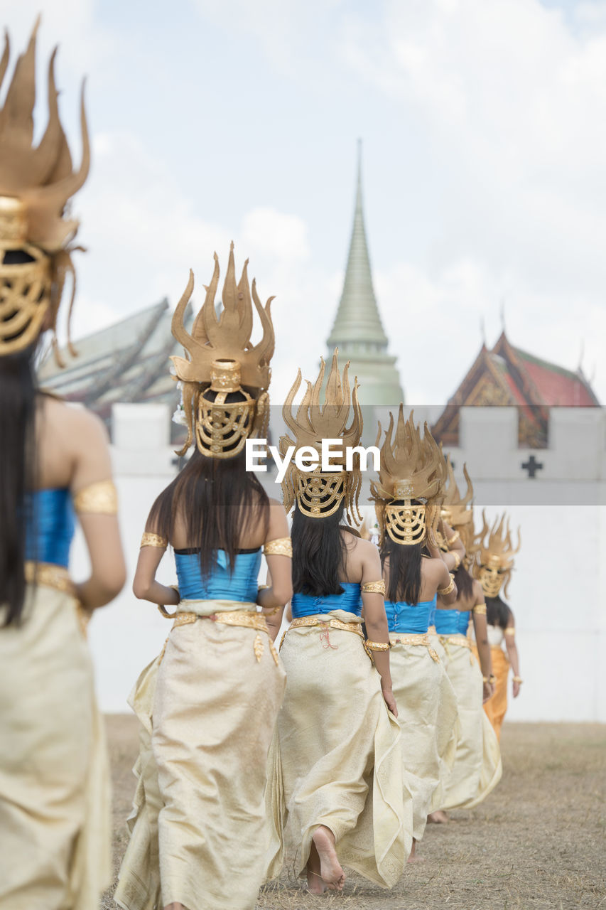 Rear view of women wearing traditional costumes while walking in row outside temple