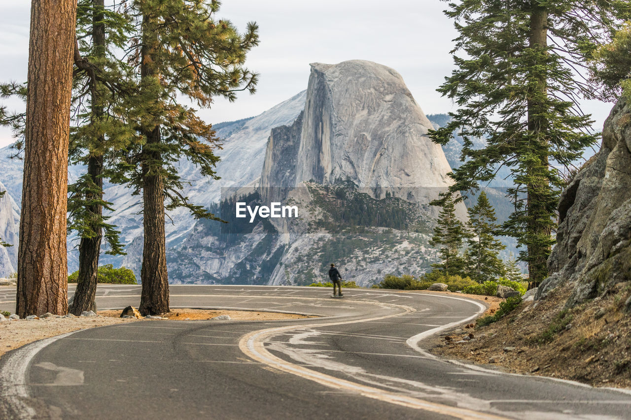 Man skateboarding on road against mountain against sky